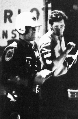 A police officer ushers Neil McBride into the Mayflower moving van.